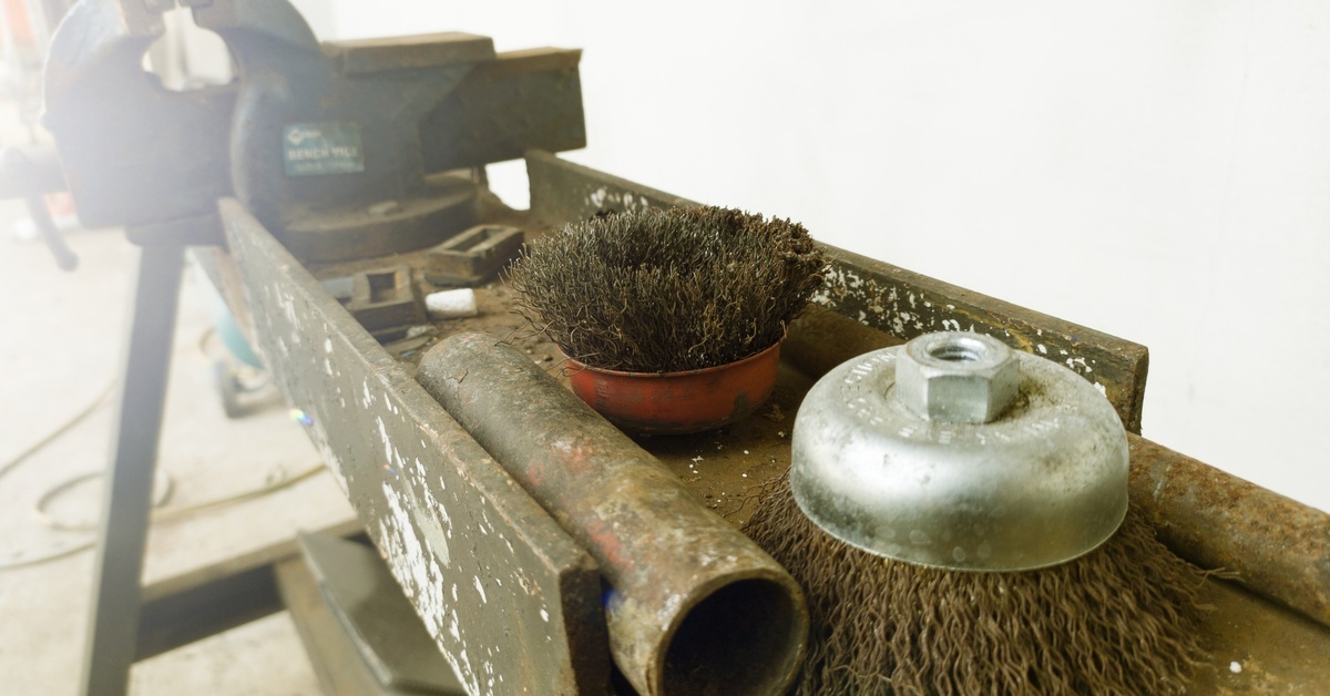 A close-up of wire brushes used for cleaning and degreasing on a construction site. The wire brushes are dusty.