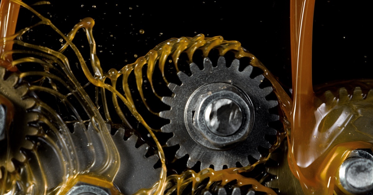 A close-up of manufacturing tooth gear wheels with industrial oils poured all over them. The oil is splashing.