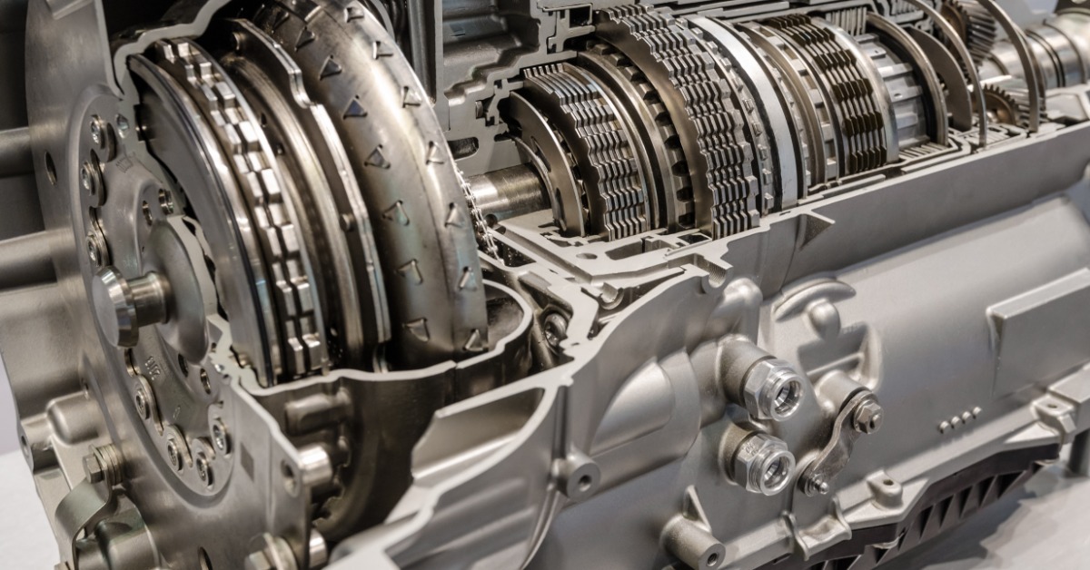 Detailed cross-section of a car gearbox reveals layered discs, rotating shafts, and machined silver casing.