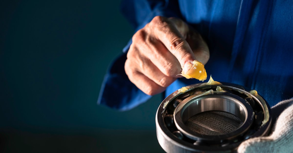 Why Degreasing Is Critical Before Lubricant Application Close-up of a gloved worker adding yellow lubricant to a circular metal bearing during industrial maintenance.
